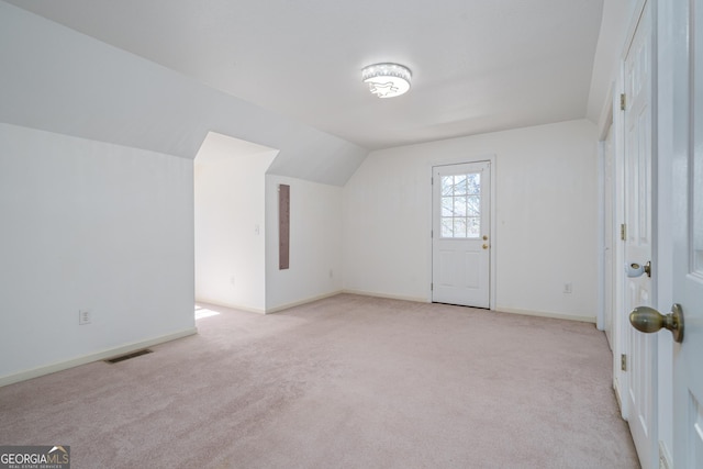 additional living space featuring lofted ceiling, light colored carpet, visible vents, and baseboards