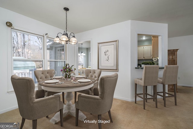 dining room featuring an inviting chandelier, light colored carpet, and baseboards