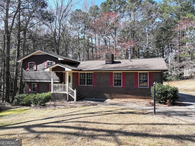 split level home featuring a front yard, brick siding, and a chimney