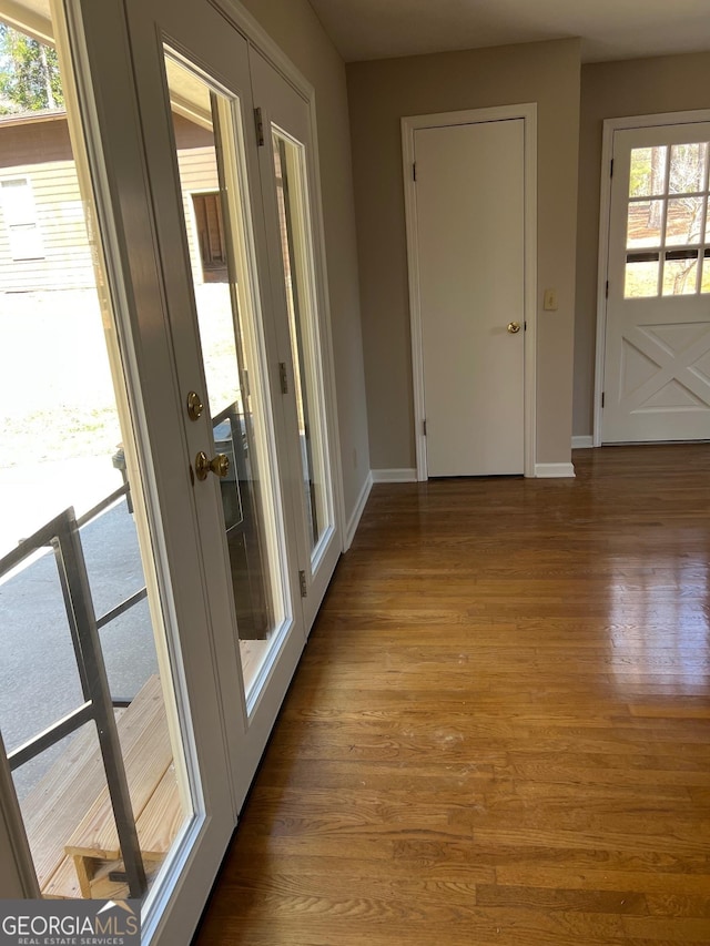 doorway featuring baseboards and wood finished floors