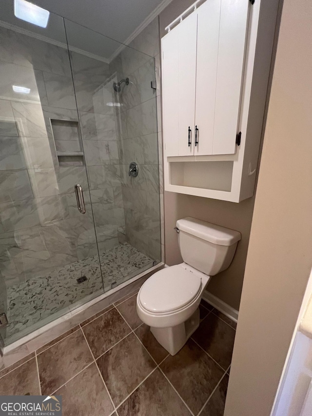 bathroom with tile patterned flooring, a shower stall, toilet, and ornamental molding