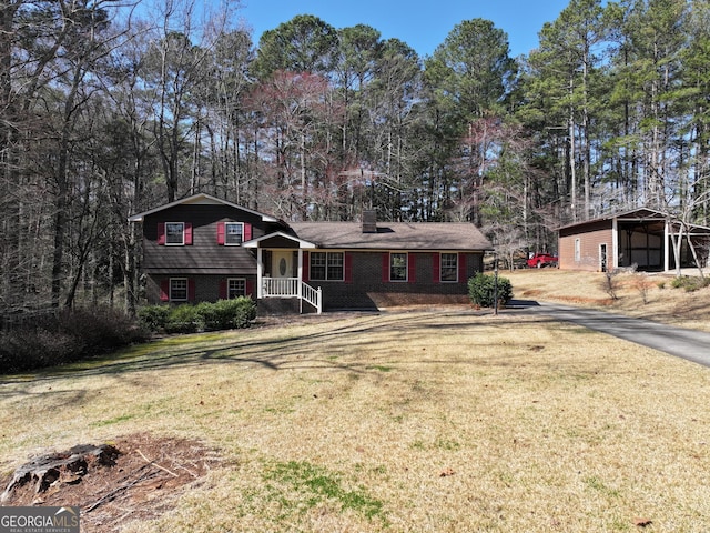 tri-level home featuring brick siding, a chimney, and a front lawn