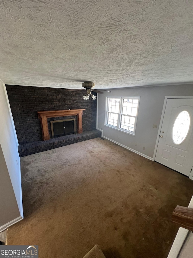 unfurnished living room featuring baseboards, a brick fireplace, a textured ceiling, and carpet