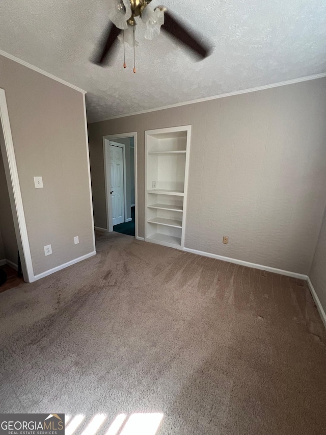 unfurnished bedroom featuring a ceiling fan, baseboards, carpet floors, ornamental molding, and a textured ceiling