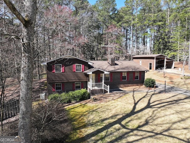 tri-level home featuring a front yard, brick siding, driveway, and a chimney