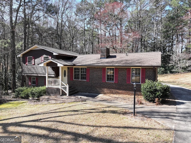 tri-level home featuring brick siding, a chimney, and a front yard