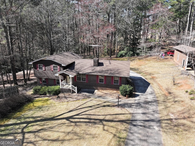 view of front of property featuring aphalt driveway, brick siding, and a front yard