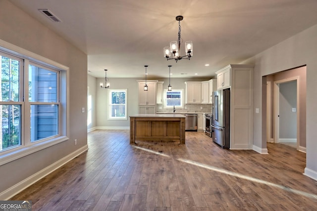 kitchen with dark wood finished floors, an inviting chandelier, backsplash, and stainless steel appliances