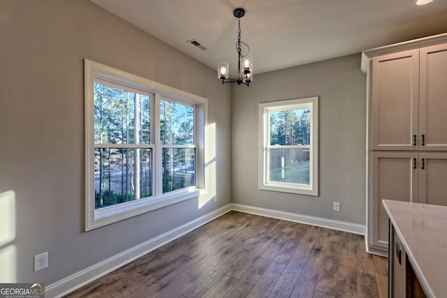 unfurnished dining area featuring an inviting chandelier, baseboards, visible vents, and dark wood-style flooring