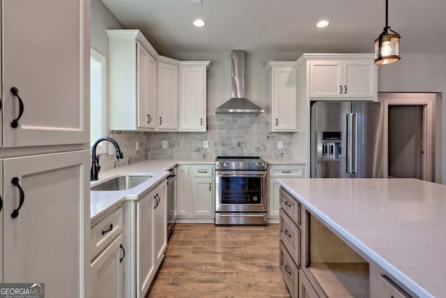 kitchen with a sink, white cabinetry, appliances with stainless steel finishes, wall chimney range hood, and decorative backsplash