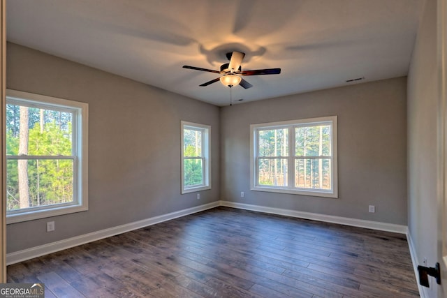 spare room featuring visible vents, baseboards, ceiling fan, and dark wood-style flooring