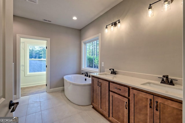 bathroom with a sink, visible vents, a freestanding bath, and tile patterned flooring