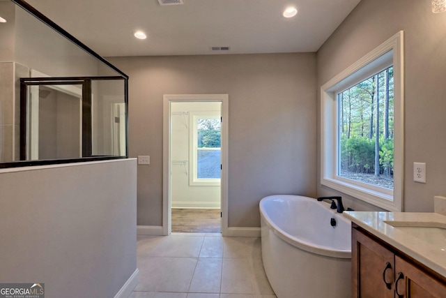 bathroom featuring tile patterned flooring, visible vents, a wealth of natural light, and a freestanding bath