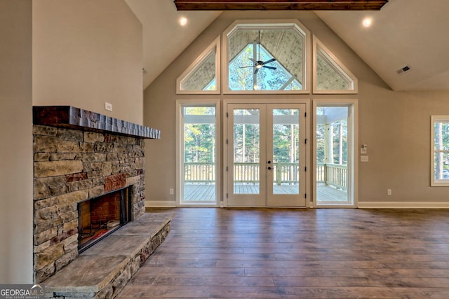 unfurnished living room with visible vents, ceiling fan, hardwood / wood-style floors, a stone fireplace, and french doors