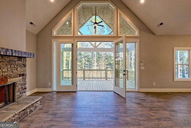 entryway featuring dark wood-type flooring, a fireplace, visible vents, and high vaulted ceiling