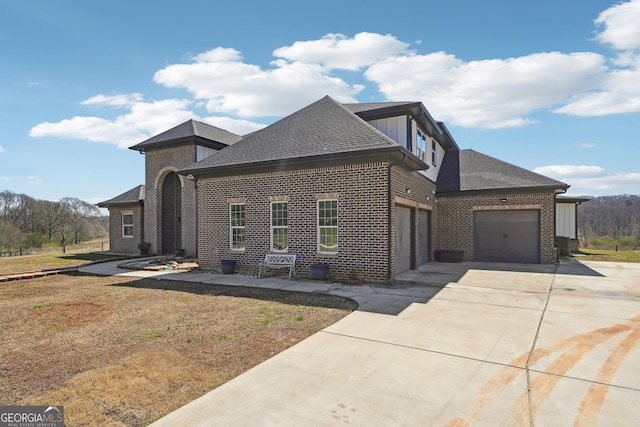 view of front of property with roof with shingles, concrete driveway, a front lawn, a garage, and brick siding