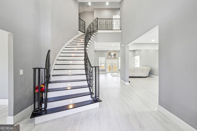 stairs featuring baseboards, a towering ceiling, and wood finished floors