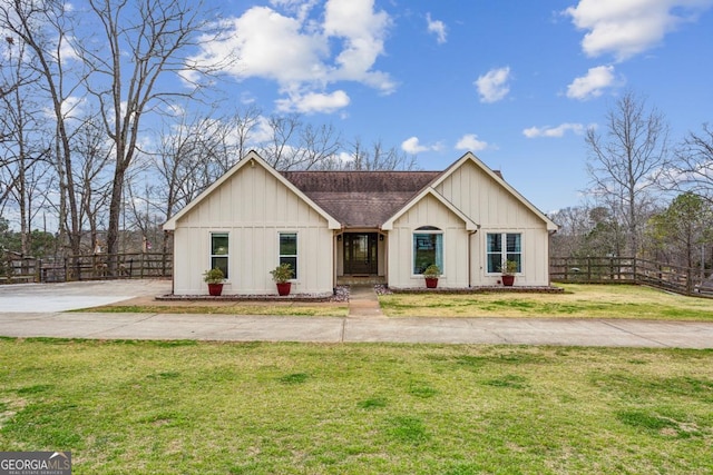 view of front of home featuring fence, driveway, a shingled roof, a front lawn, and board and batten siding