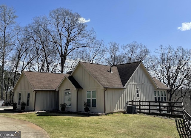 modern farmhouse style home featuring central air condition unit, board and batten siding, a front lawn, and a shingled roof