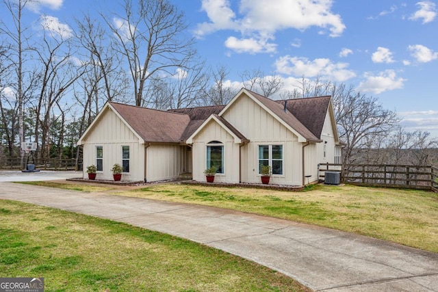 view of front of property with board and batten siding, a front lawn, fence, roof with shingles, and driveway