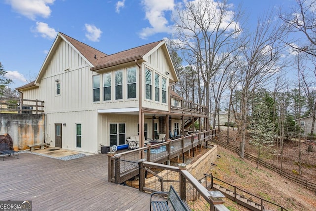 back of property with a wooden deck, board and batten siding, and stairway