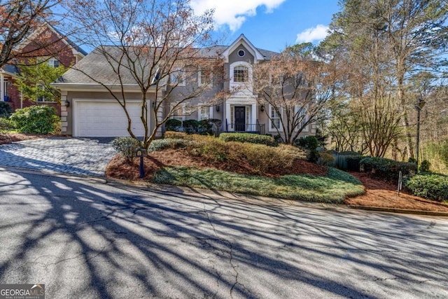 view of front of property featuring stucco siding, decorative driveway, and a garage