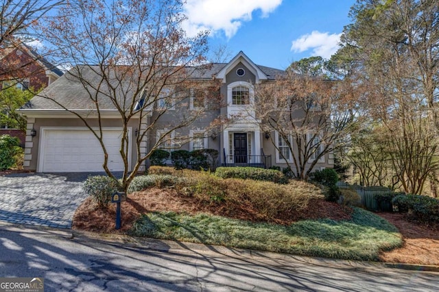 view of front of home with decorative driveway, an attached garage, and stucco siding