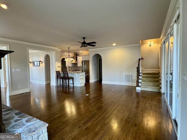 living area with stairway, dark wood-style flooring, arched walkways, ceiling fan, and visible vents