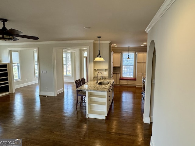 kitchen with a breakfast bar area, open shelves, a sink, arched walkways, and a ceiling fan