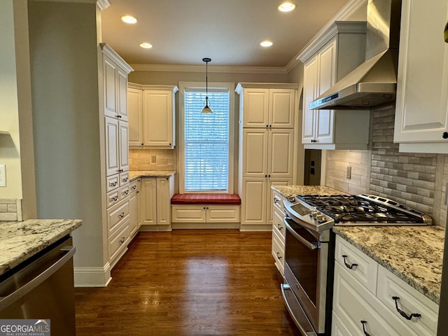 kitchen featuring wall chimney range hood, dark wood-style floors, light stone counters, and appliances with stainless steel finishes