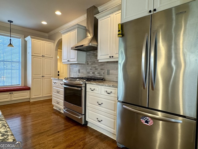 kitchen featuring crown molding, appliances with stainless steel finishes, dark wood-style floors, wall chimney range hood, and decorative backsplash