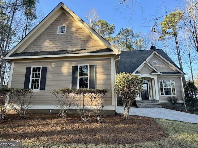 view of front of house featuring a chimney and a shingled roof