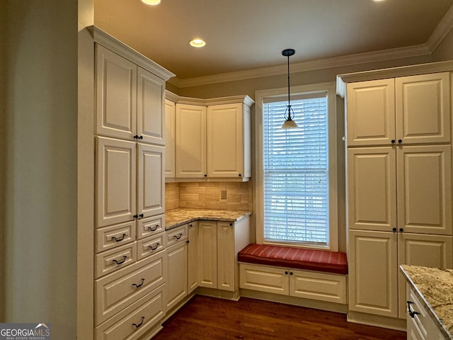 kitchen with crown molding, light stone countertops, white cabinetry, hanging light fixtures, and dark wood-style floors