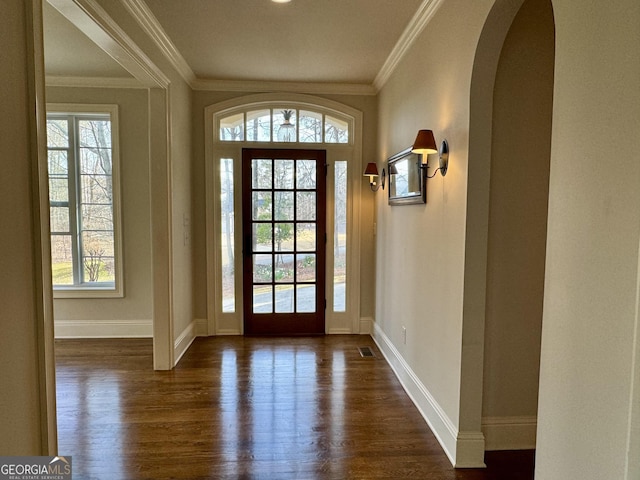 entryway featuring visible vents, baseboards, ornamental molding, dark wood finished floors, and arched walkways