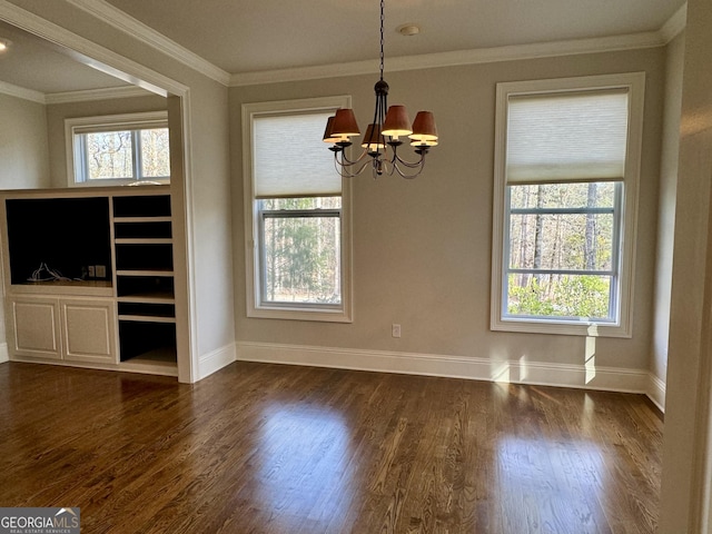 unfurnished dining area with an inviting chandelier, crown molding, baseboards, and dark wood finished floors