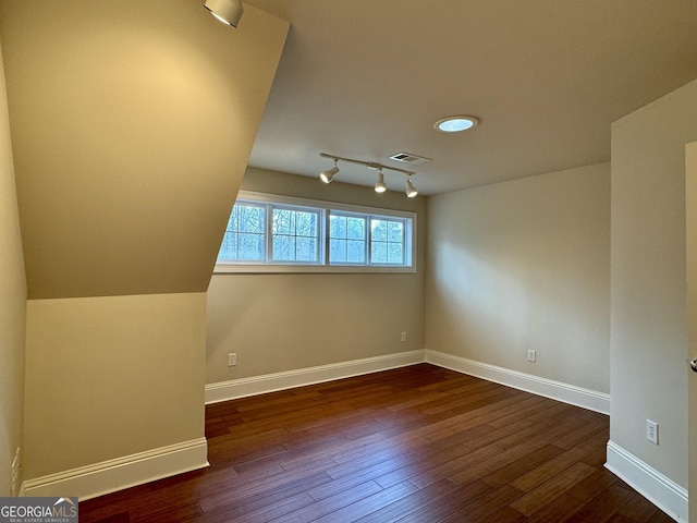 unfurnished room featuring baseboards, visible vents, track lighting, and dark wood-type flooring