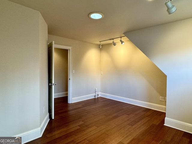 unfurnished room with track lighting, baseboards, and wood finished floors