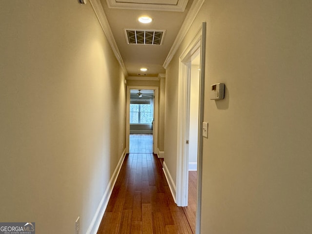 hallway with dark wood-type flooring, baseboards, visible vents, and crown molding