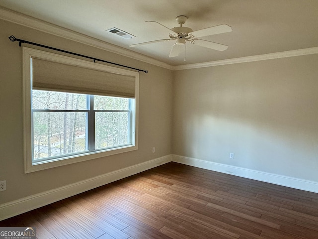 spare room with crown molding, dark wood-type flooring, baseboards, visible vents, and a ceiling fan