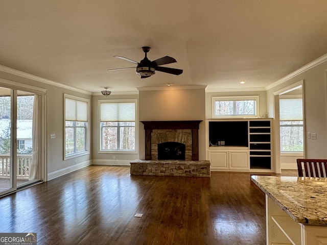 unfurnished living room with crown molding, dark wood-type flooring, baseboards, a ceiling fan, and a fireplace