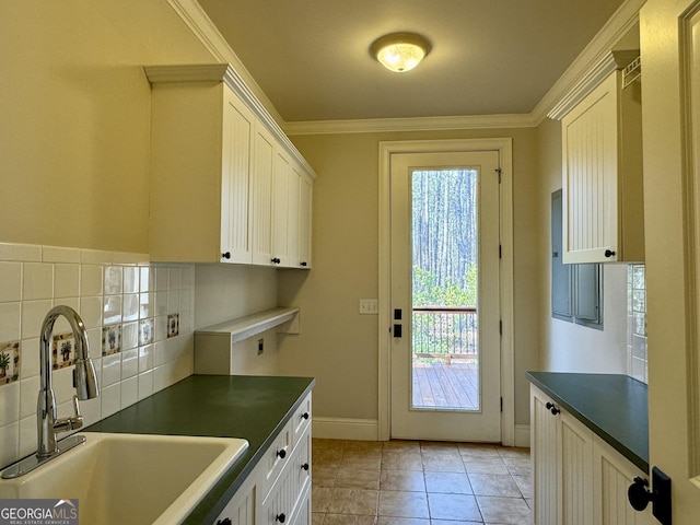 kitchen featuring white cabinets, crown molding, dark countertops, tasteful backsplash, and a sink