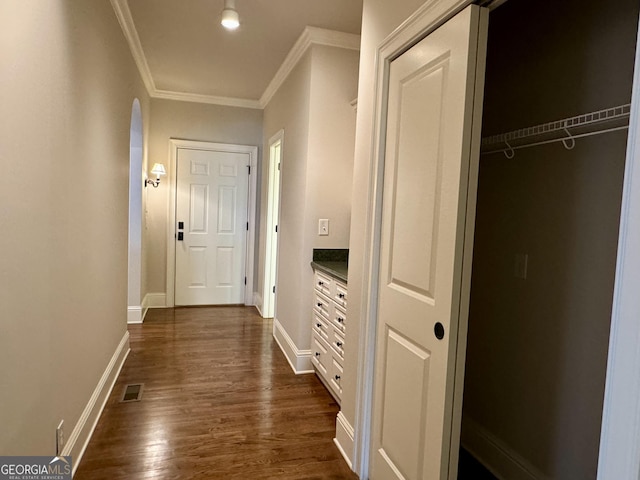 hall featuring visible vents, ornamental molding, baseboards, and dark wood finished floors