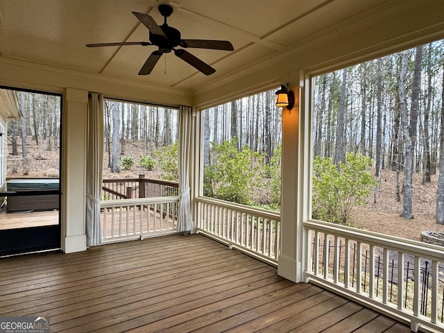 unfurnished sunroom with crown molding, a healthy amount of sunlight, a ceiling fan, and hardwood / wood-style flooring
