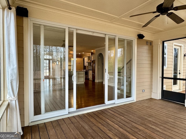 unfurnished sunroom featuring arched walkways and ceiling fan