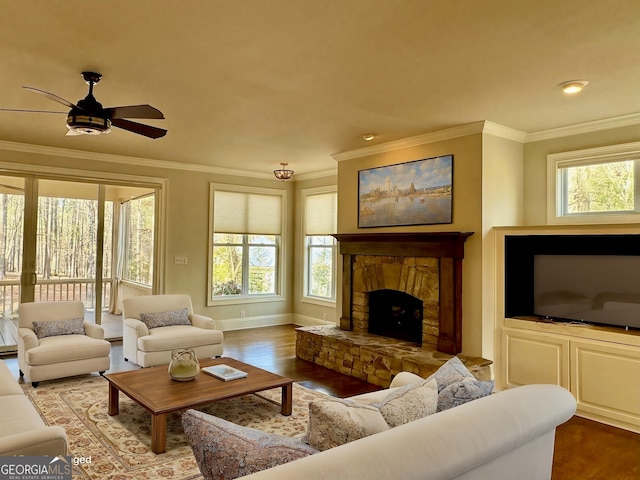 living room featuring ornamental molding, baseboards, a ceiling fan, a fireplace, and wood finished floors
