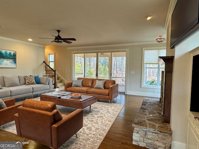 living area with dark wood-type flooring, ornamental molding, a ceiling fan, and a wealth of natural light