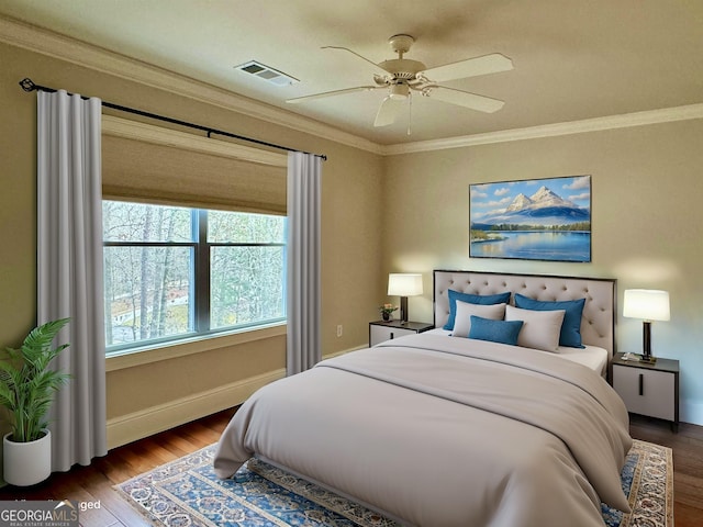 bedroom featuring visible vents, baseboards, ornamental molding, wood finished floors, and a ceiling fan