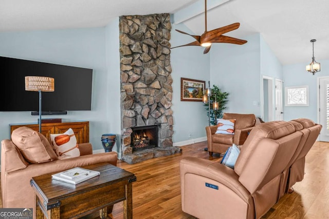 living area featuring wood finished floors, a ceiling fan, baseboards, high vaulted ceiling, and a stone fireplace