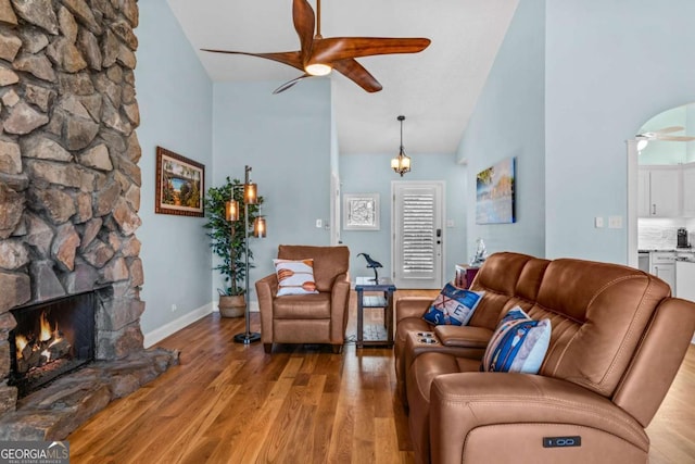 living area featuring a fireplace, wood finished floors, a ceiling fan, and baseboards