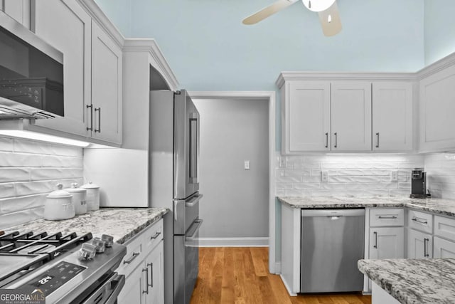 kitchen featuring backsplash, appliances with stainless steel finishes, white cabinetry, and a ceiling fan